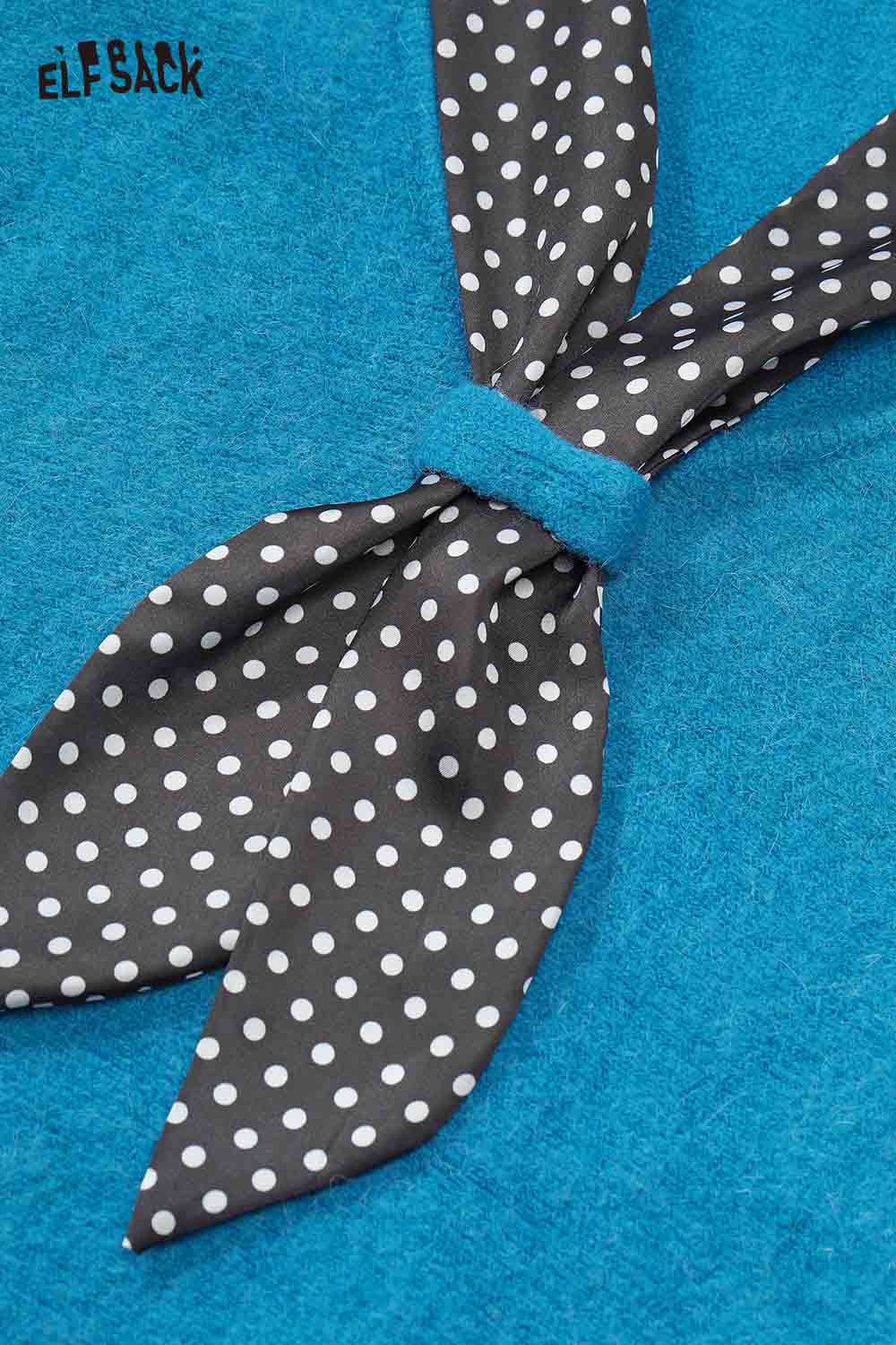 Close-up of ELFSACK bat sleeve polka dot sweater featuring a tied polka dot ribbon detail on a vibrant blue background