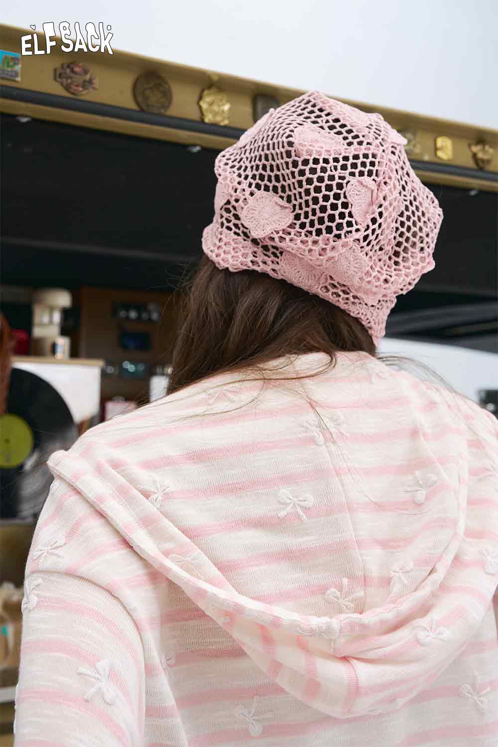 ELFSACK model wearing oversized striped cardigan for women in pink and white hooded knit with bow motifs and crochet beanie