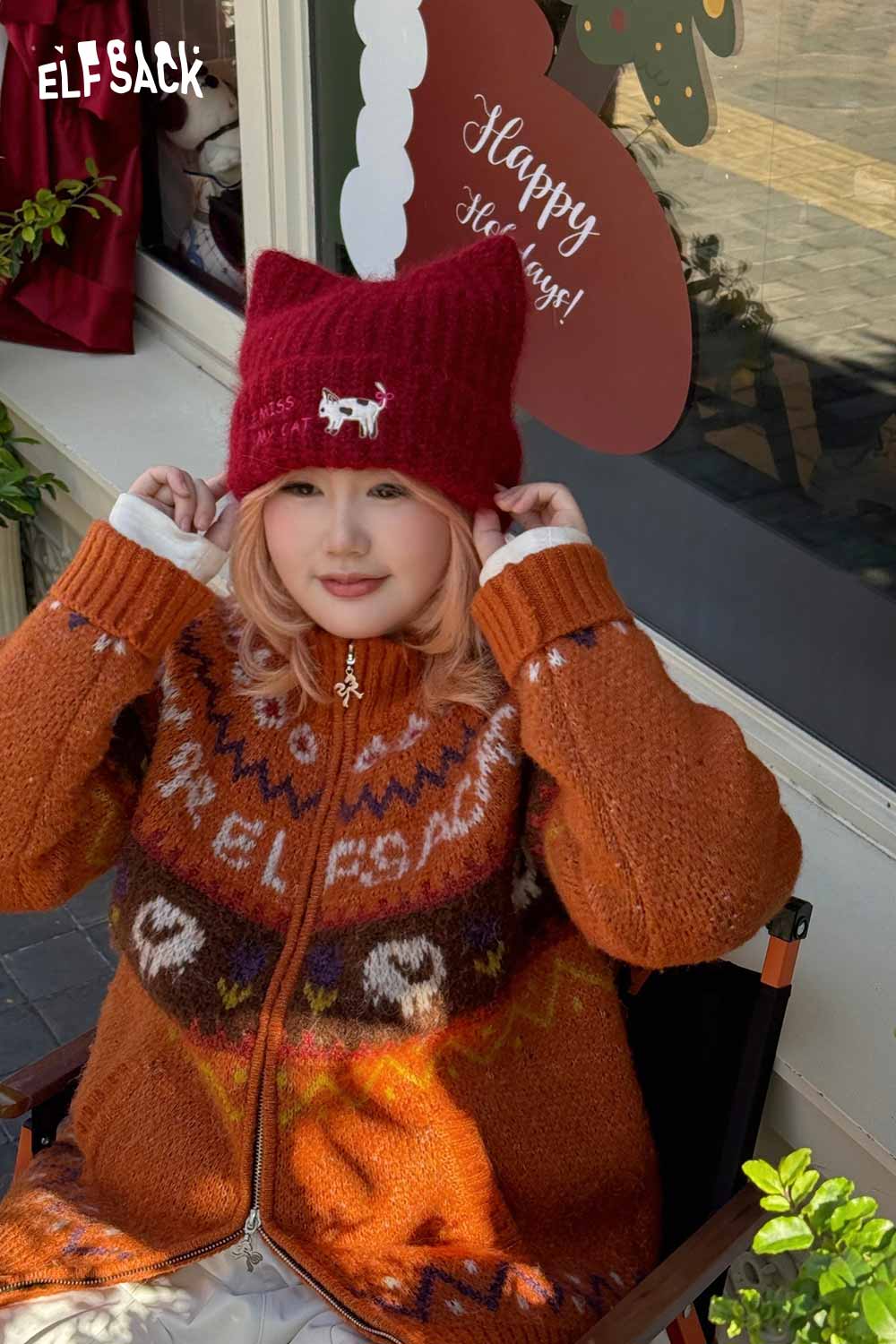 ELFSACK cat ear beanie for women in red, worn by a model with a cozy cardigan