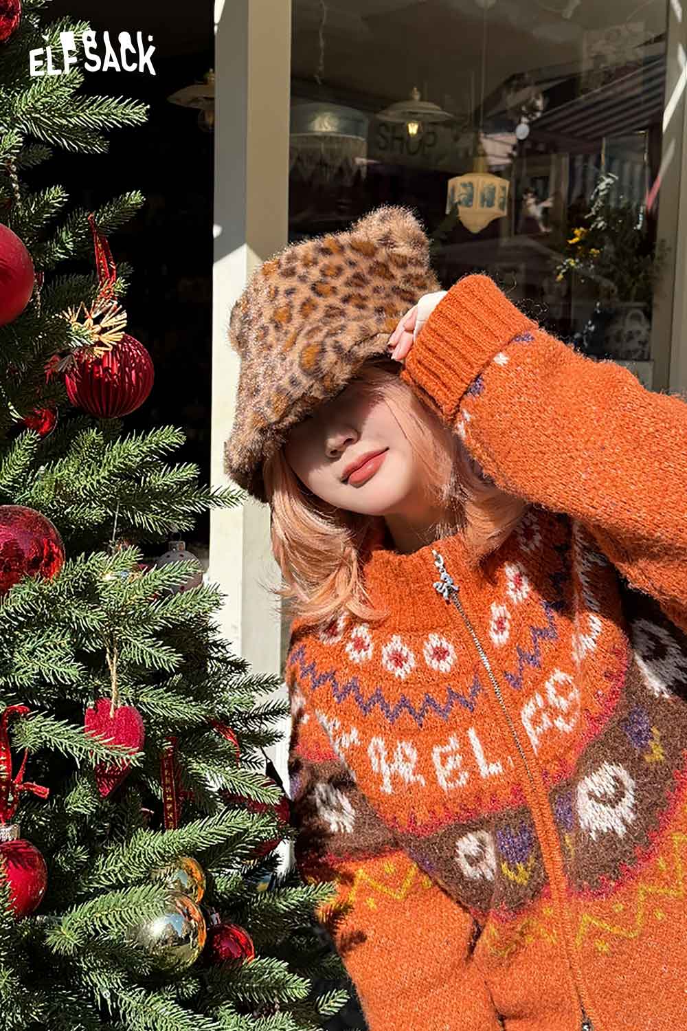 ELFSACK cat ear leopard plush hat worn with an oversized orange sweater in a festive setting