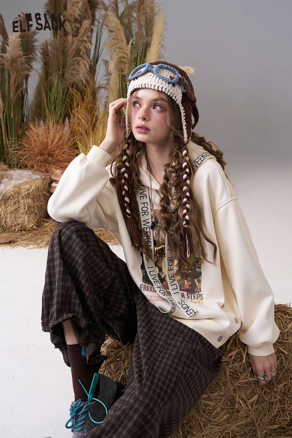 Color blocked crocheted ear flap beanie accessorizing a cozy ELFSACK outfit in a rustic setting