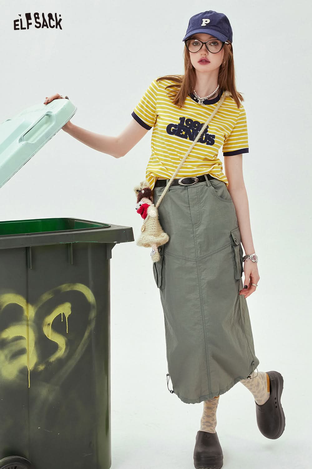 ELFSACK yellow and black Contrasting Stripe graphic T-shirt worn with green cargo skirt and navy cap