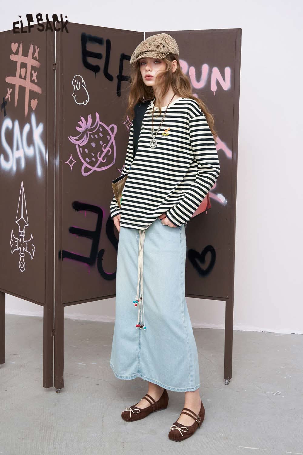 ELFSACK model wearing cotton striped long sleeve tee in black white relaxed fit paired with denim maxi skirt and cap
