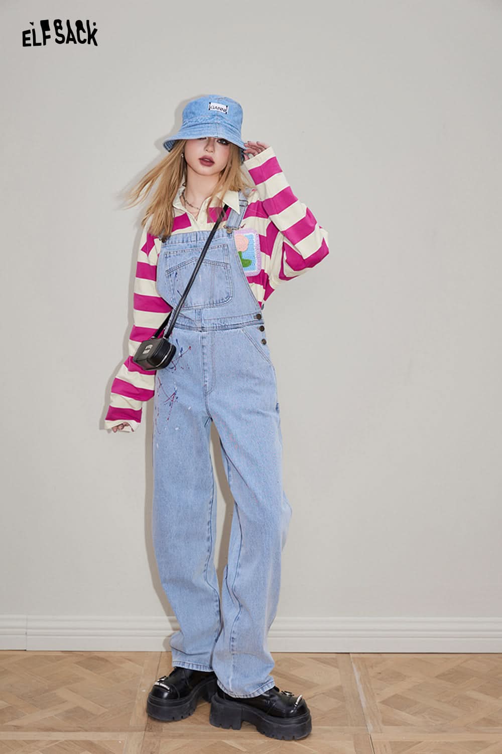 ELFSACK T-shirt with Croche Flower Striped design worn under denim overalls and paired with a blue bucket hat