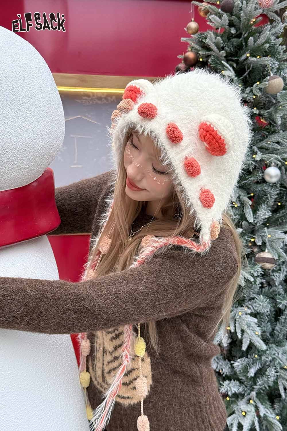 Woman wearing a cute 3D ear beanie hat with playful designs, posing beside a snowman