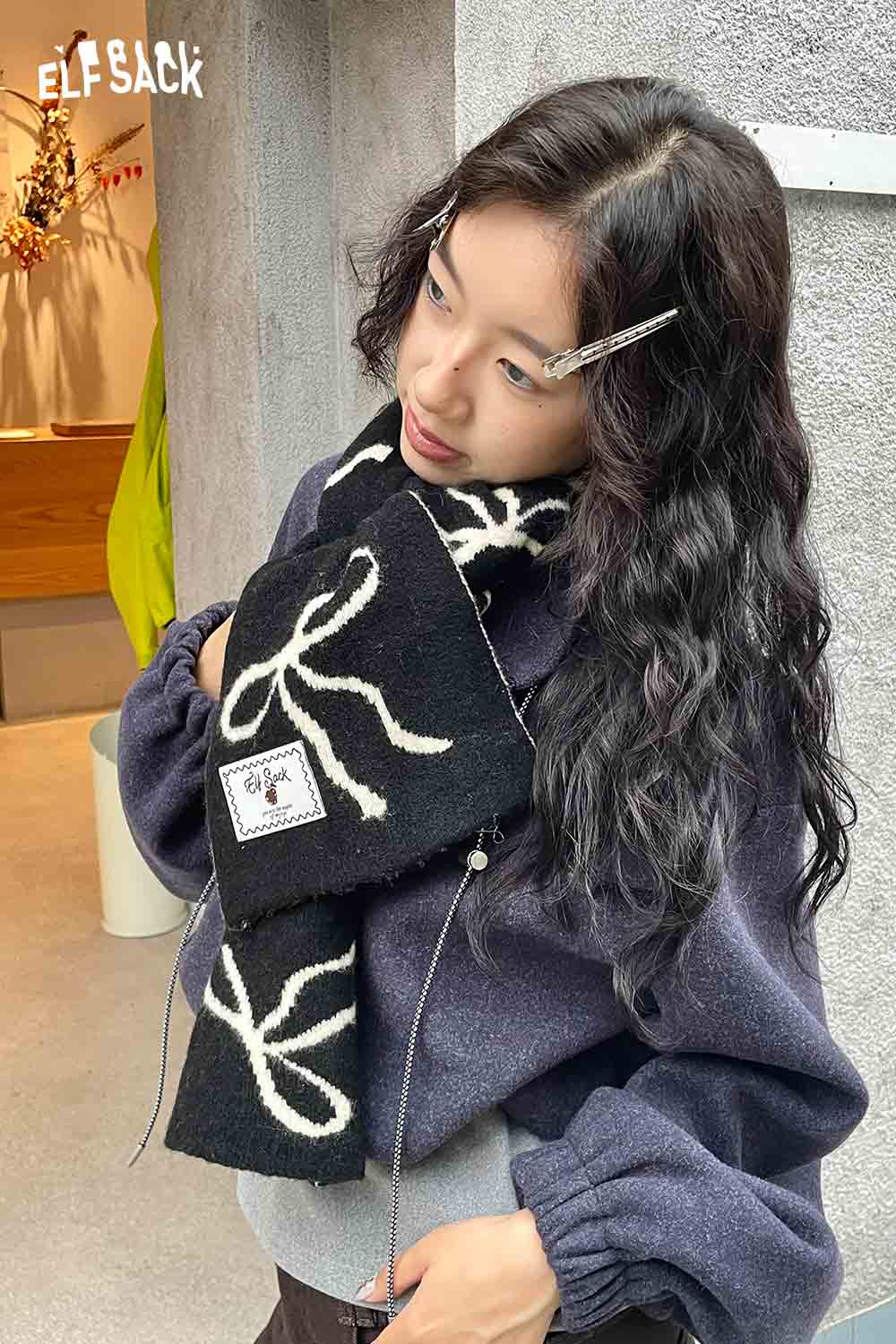 ELFSACK bow graphic neck warmer in black and white, stylishly worn with a cozy outfit