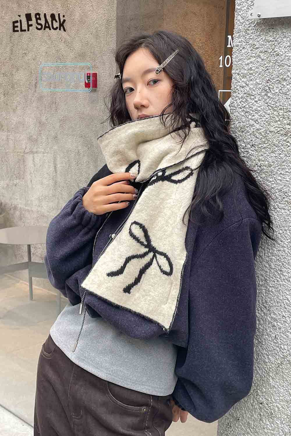 ELFSACK bow graphic neck warmer in cream with black bow design, perfect for stylish winter layering