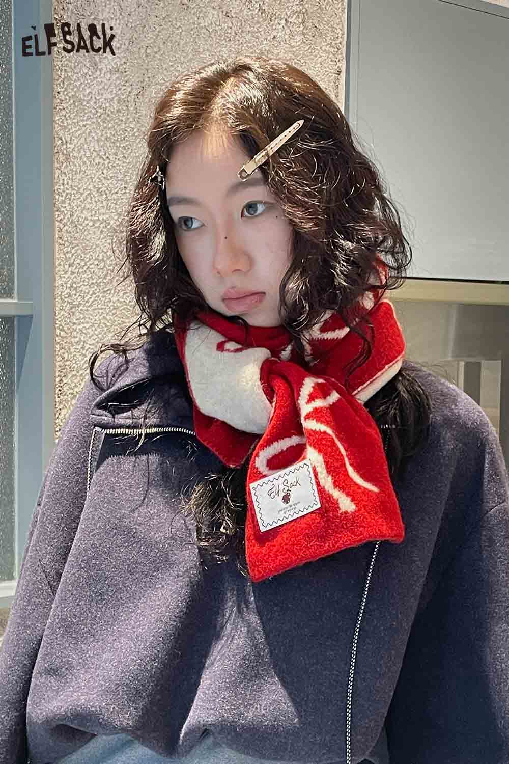 ELFSACK bow graphic neck warmer in red and white, stylishly worn by a model for winter fashion