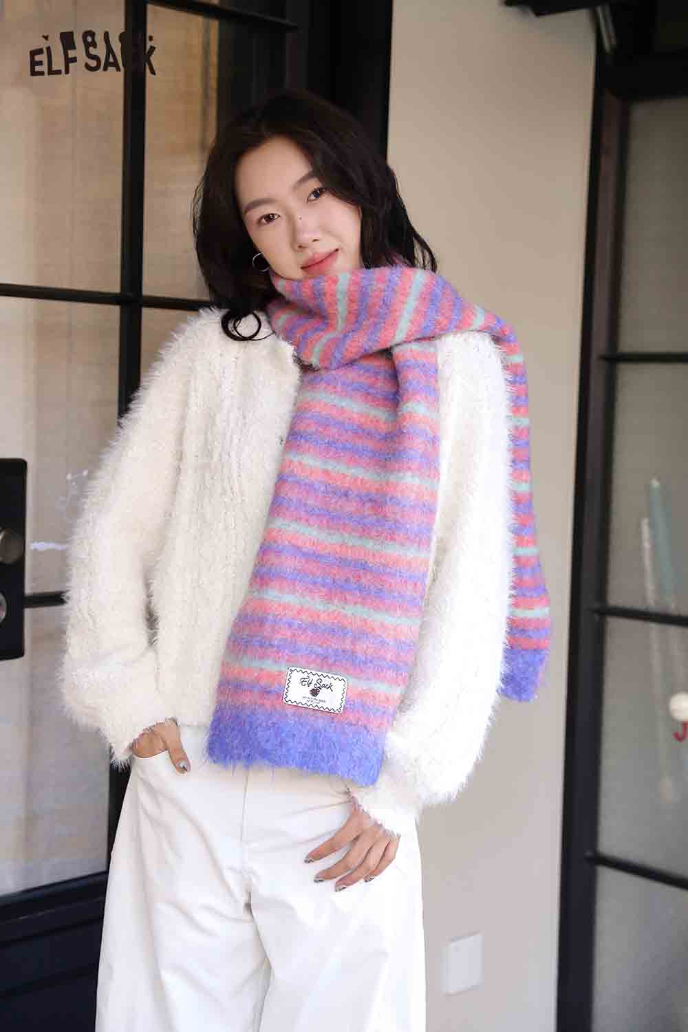 Cozy ELFSACK Christmas striped scarf for women in pink and blue hues paired with a fluffy white sweater