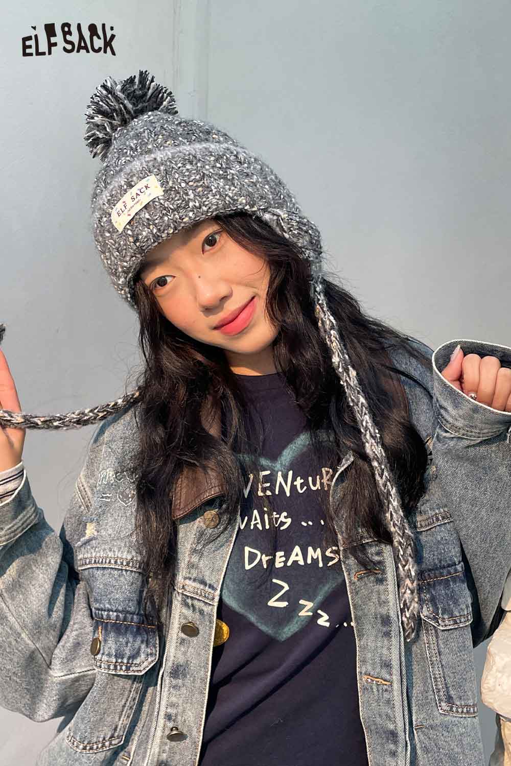 Stylish ELFSACK cute striped pom beanie for women paired with a denim jacket and playful smile