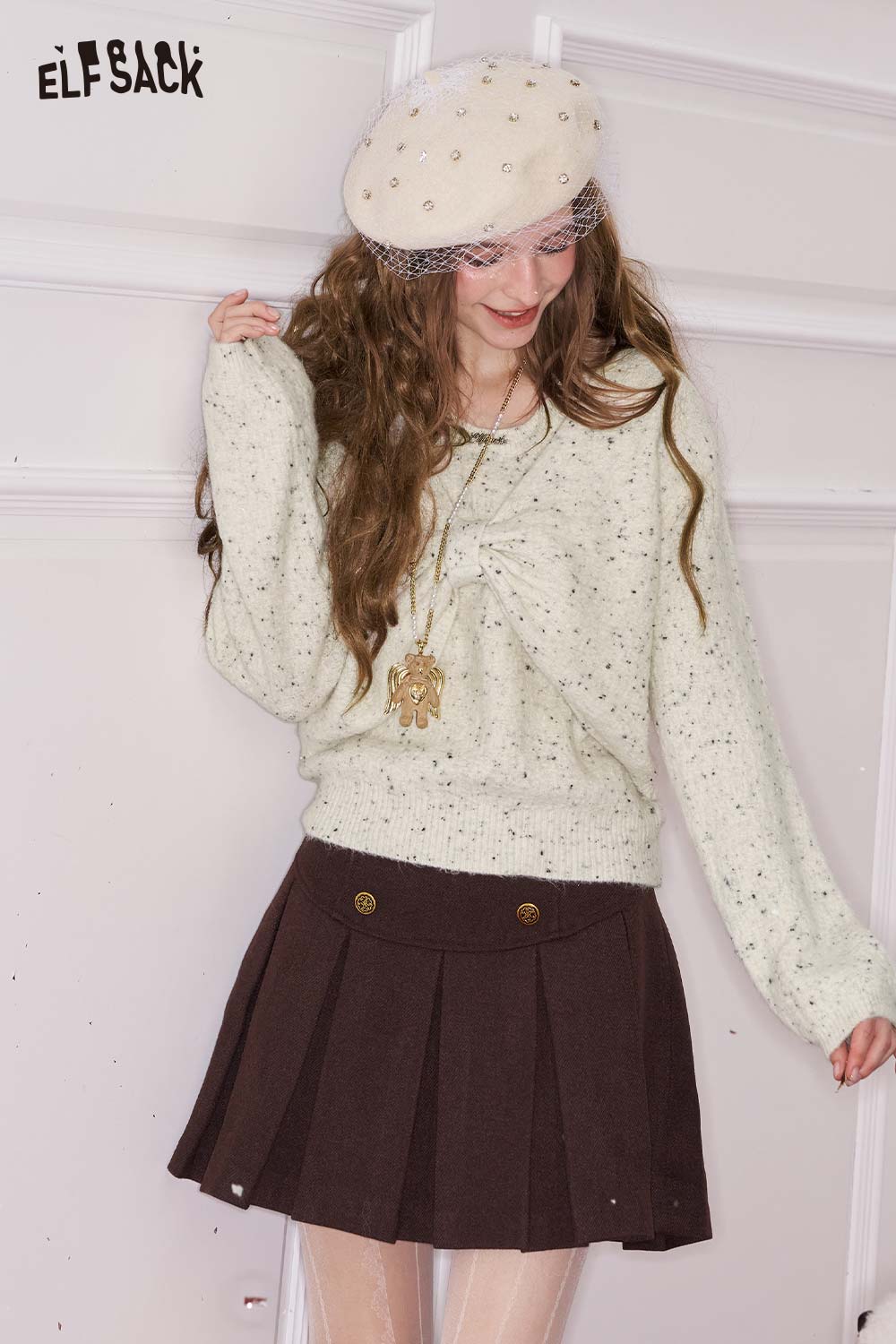 ELFSACK bow embellished cutout sweater in soft knit with a playful design, styled with a pleated skirt