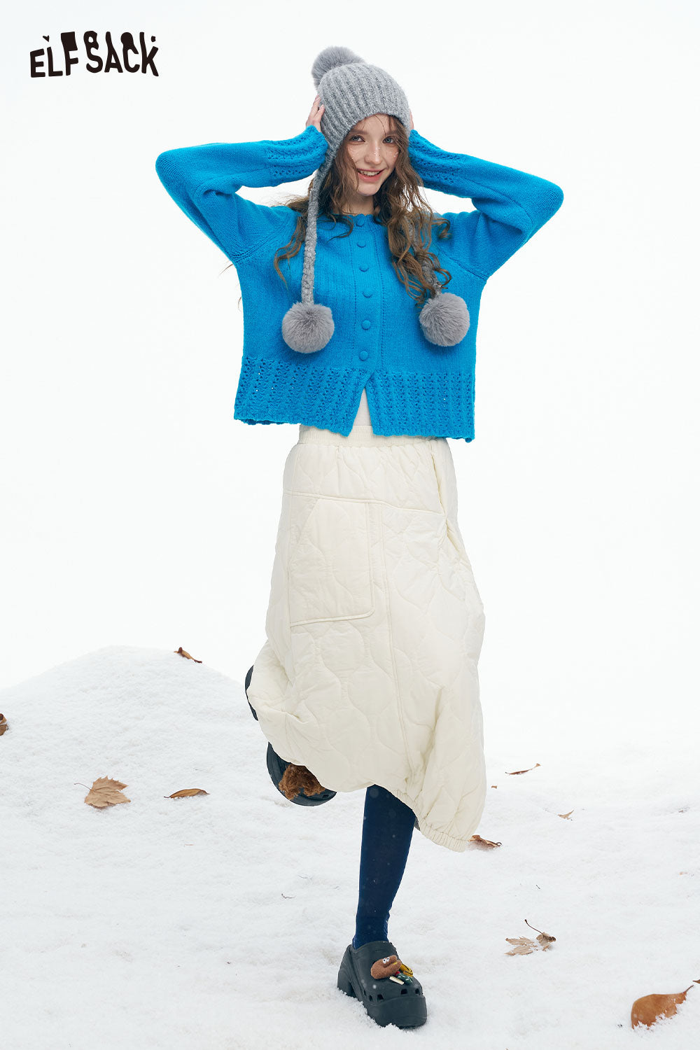 Woman wearing a cute knit embroidered sweater for women with a pom-pom hat, standing in snow