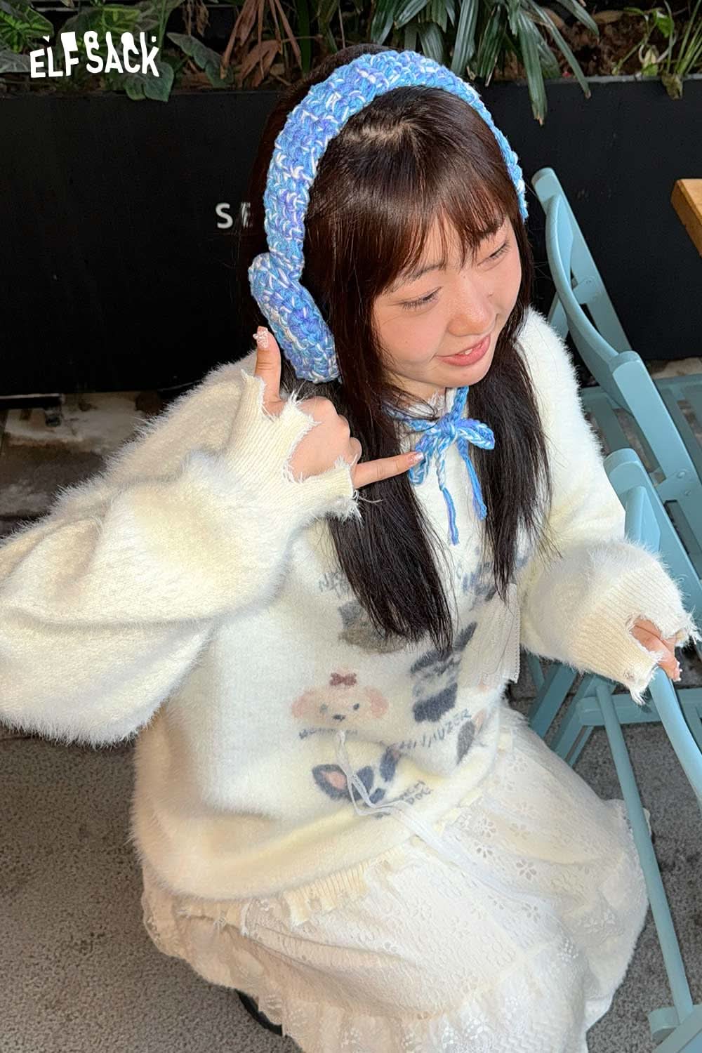 ELFSACK hand-knitted ear warmers in blue worn by a girl in a cozy white sweater