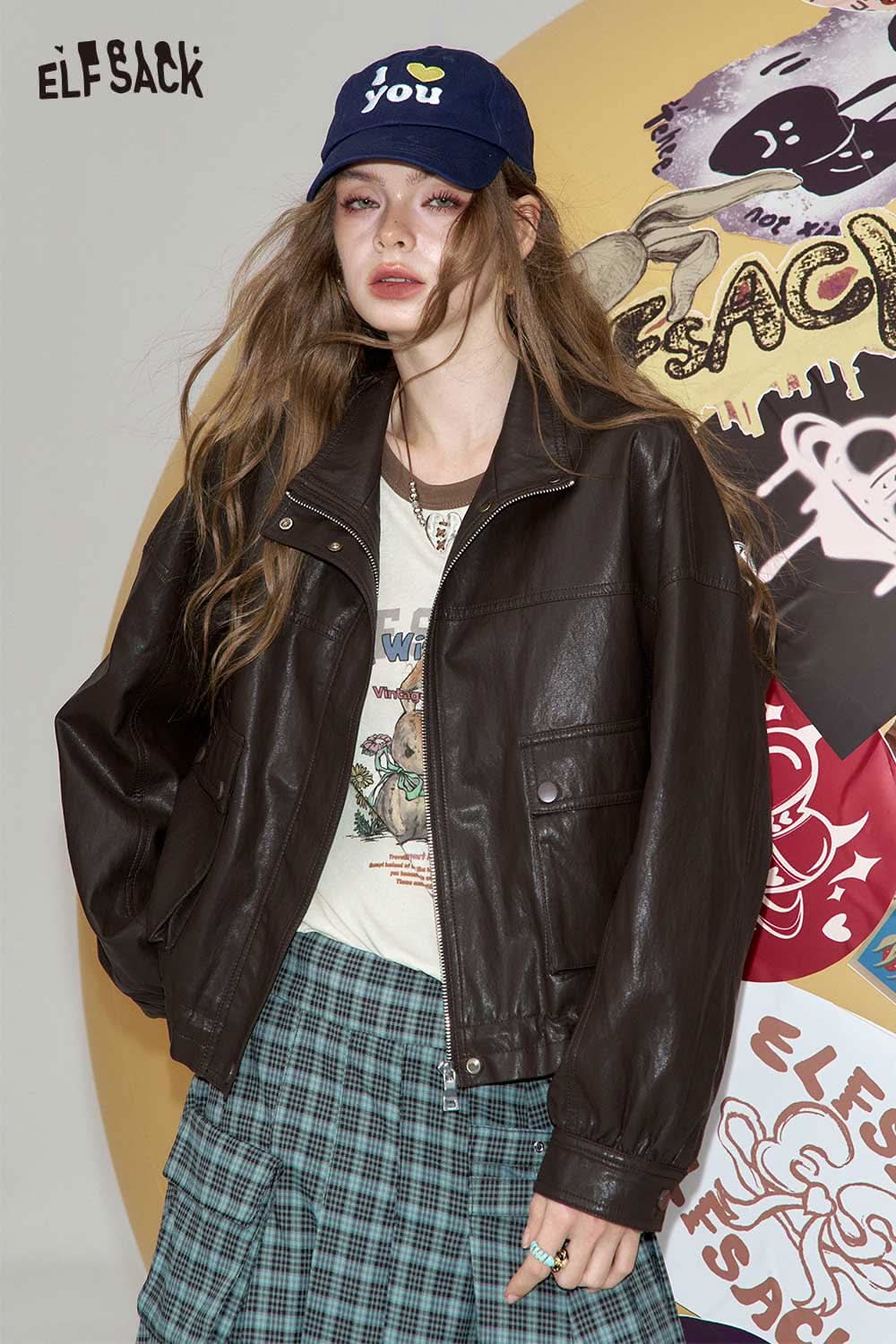 Trendy model wearing women's raglan sleeve graphic tee with a brown leather jacket and plaid skirt