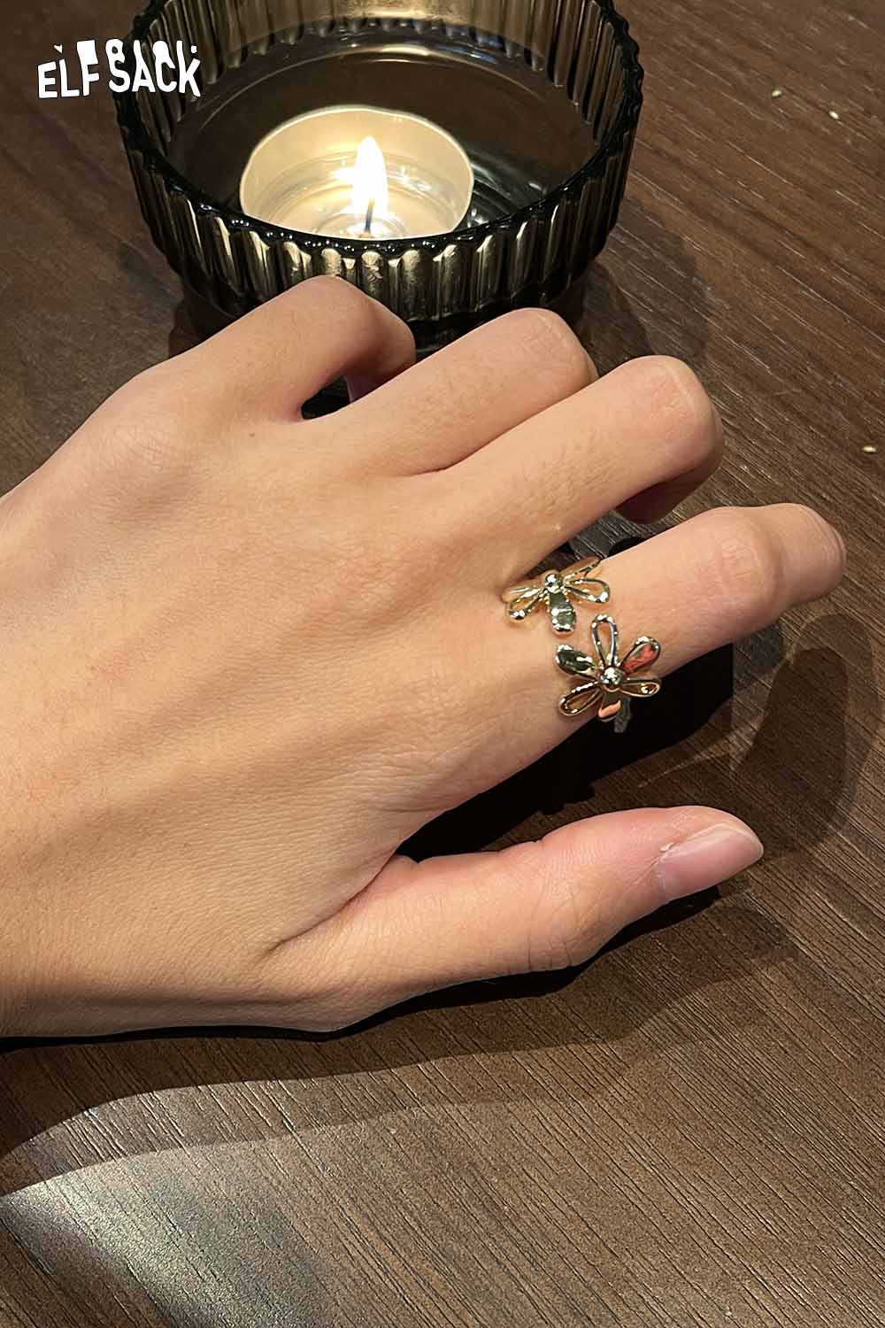 Hand wearing a floral copper statement ring surrounded by warm candlelight for elegant style