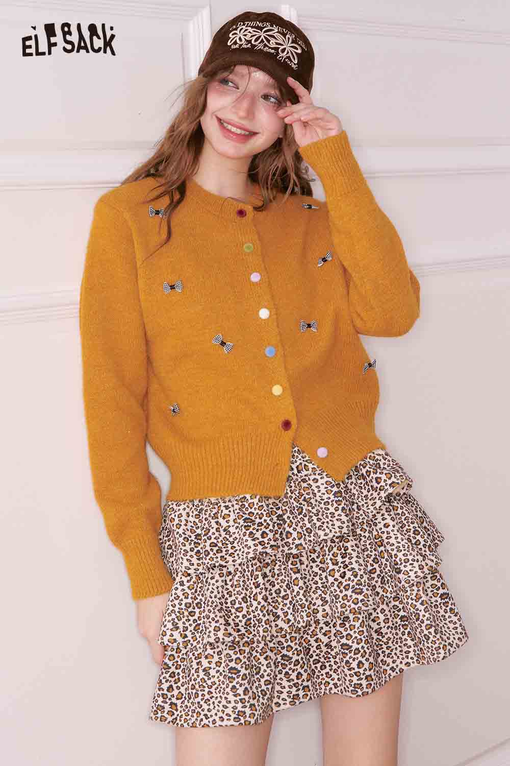 ELFSACK girly bow cardigan in mustard with colorful buttons, styled with a ruffled leopard print skirt