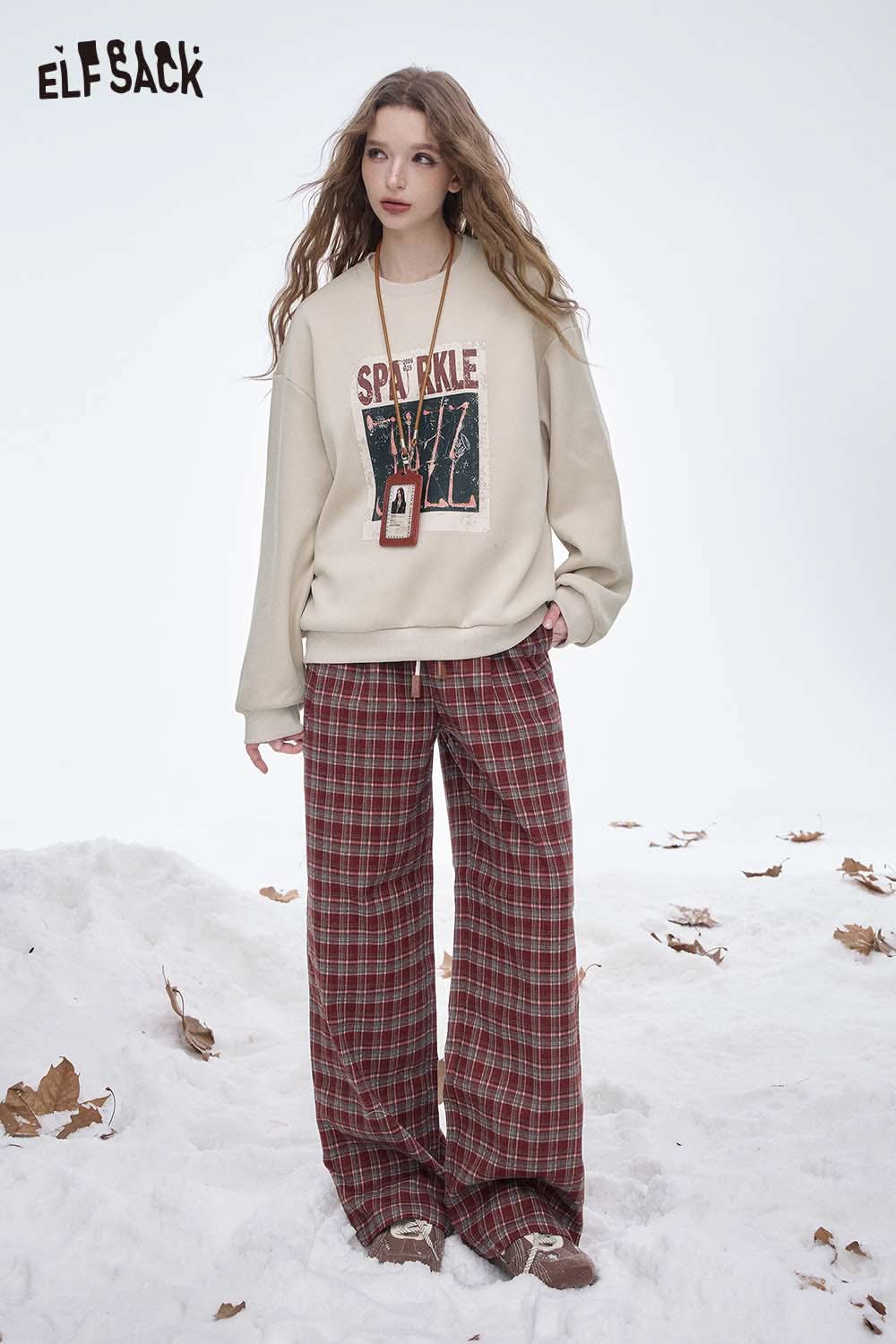 Women's graphic sweatshirt from ELFSACK with a 'Sparkle' design, styled with plaid pants for a casual look