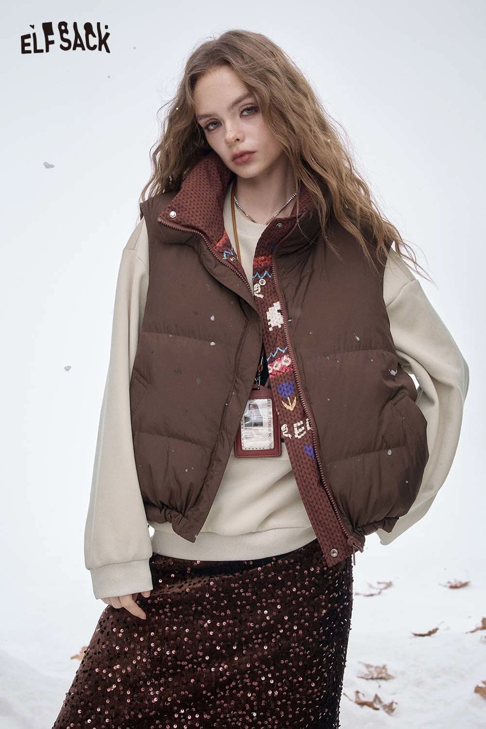 ELFSACK women's graphic sweatshirt styled under a brown puffer vest in a winter setting