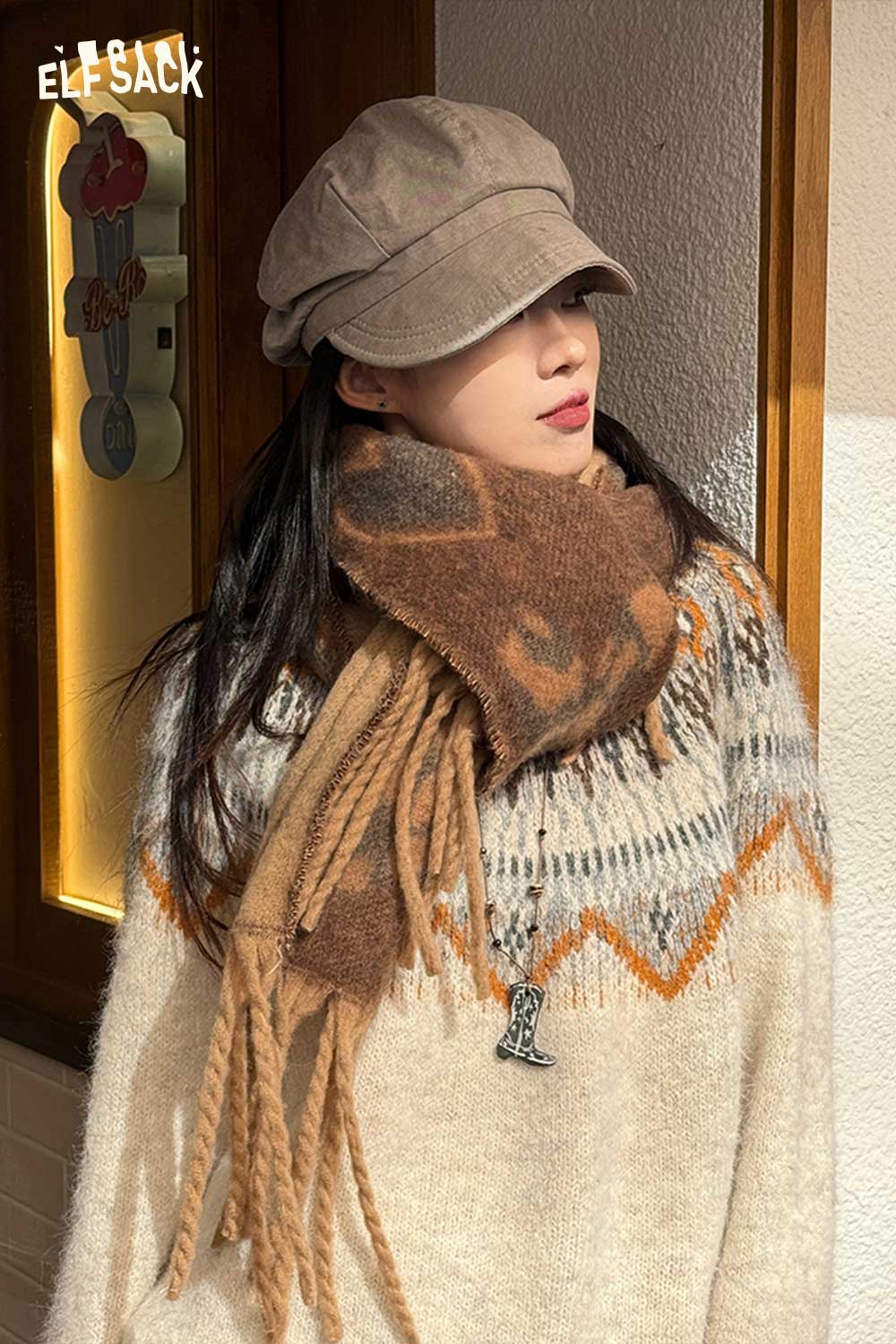 ELFSACK leopard heart fringe scarf in brown tones styled with a cozy knit sweater and cap