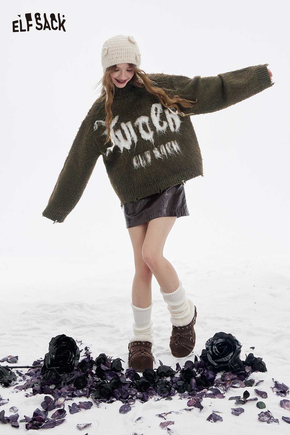 ELFSACK loose letter graphic fringe sweater in olive green, styled with a short skirt and cozy accessories