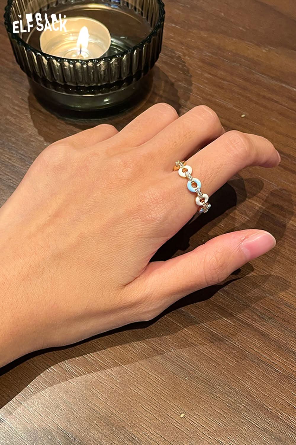 ELFSACK minimalist copper coin ring displayed on a hand next to a lit candle for an elegant look