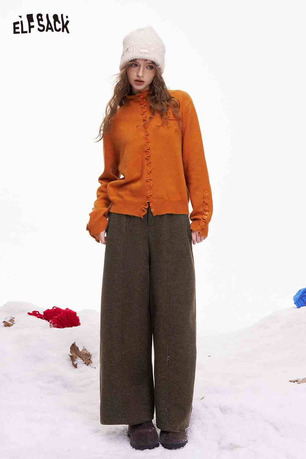 ELFSACK minimalist wide leg pants women styled with an orange cardigan and knit hat in a snowy setting