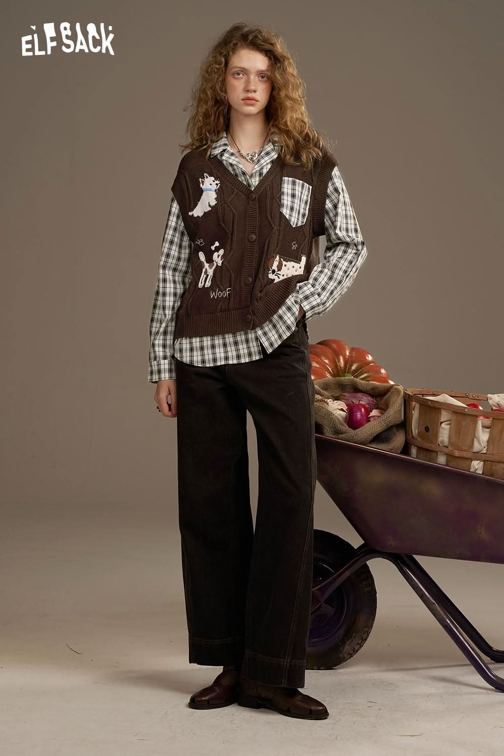 Model wearing a playful embroidered knit top layered over a checkered shirt with casual wide-leg pants