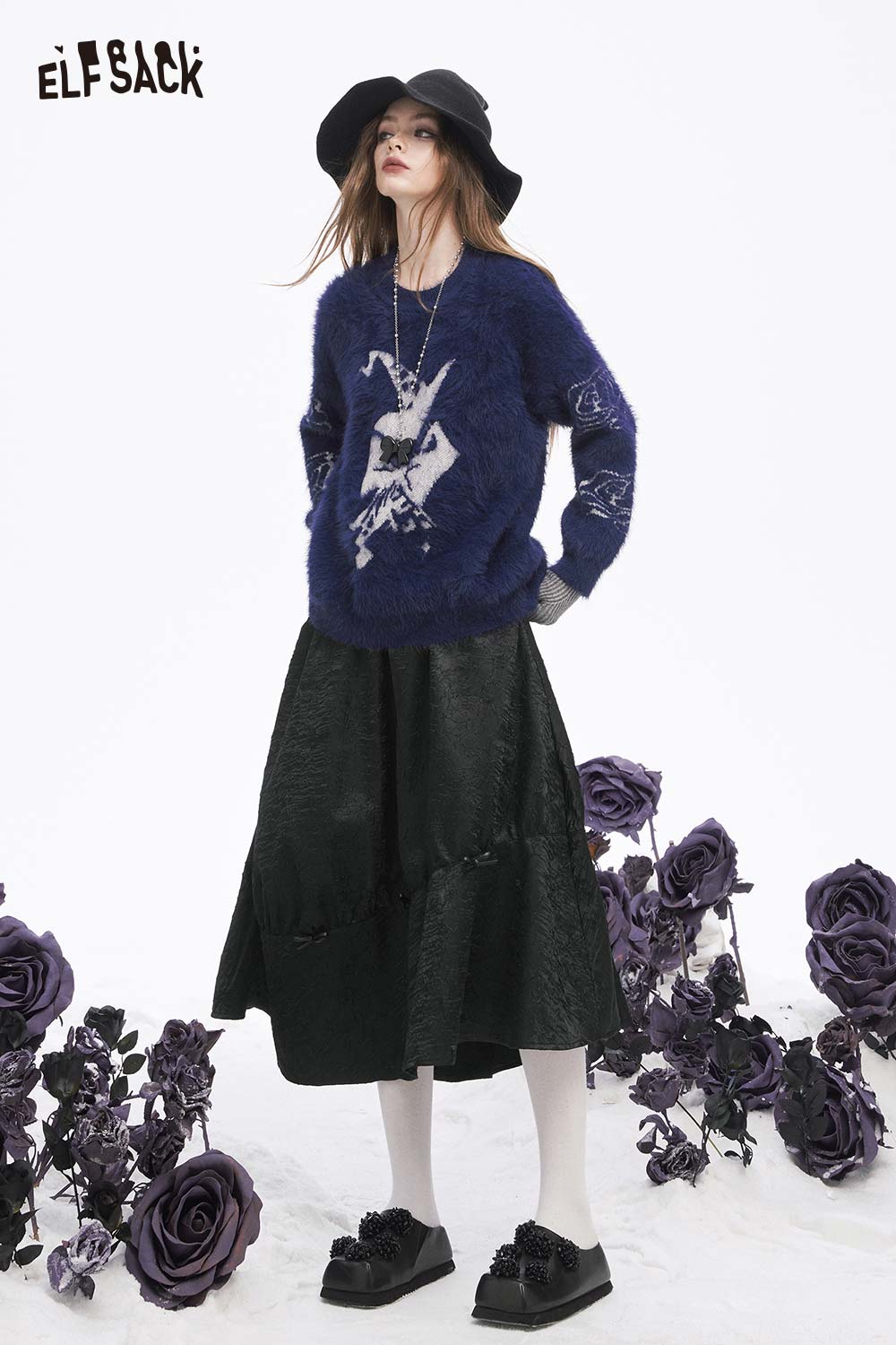 Stylish ELFSACK model wearing a pleated A-line long skirt paired with a cozy sweater and accessories
