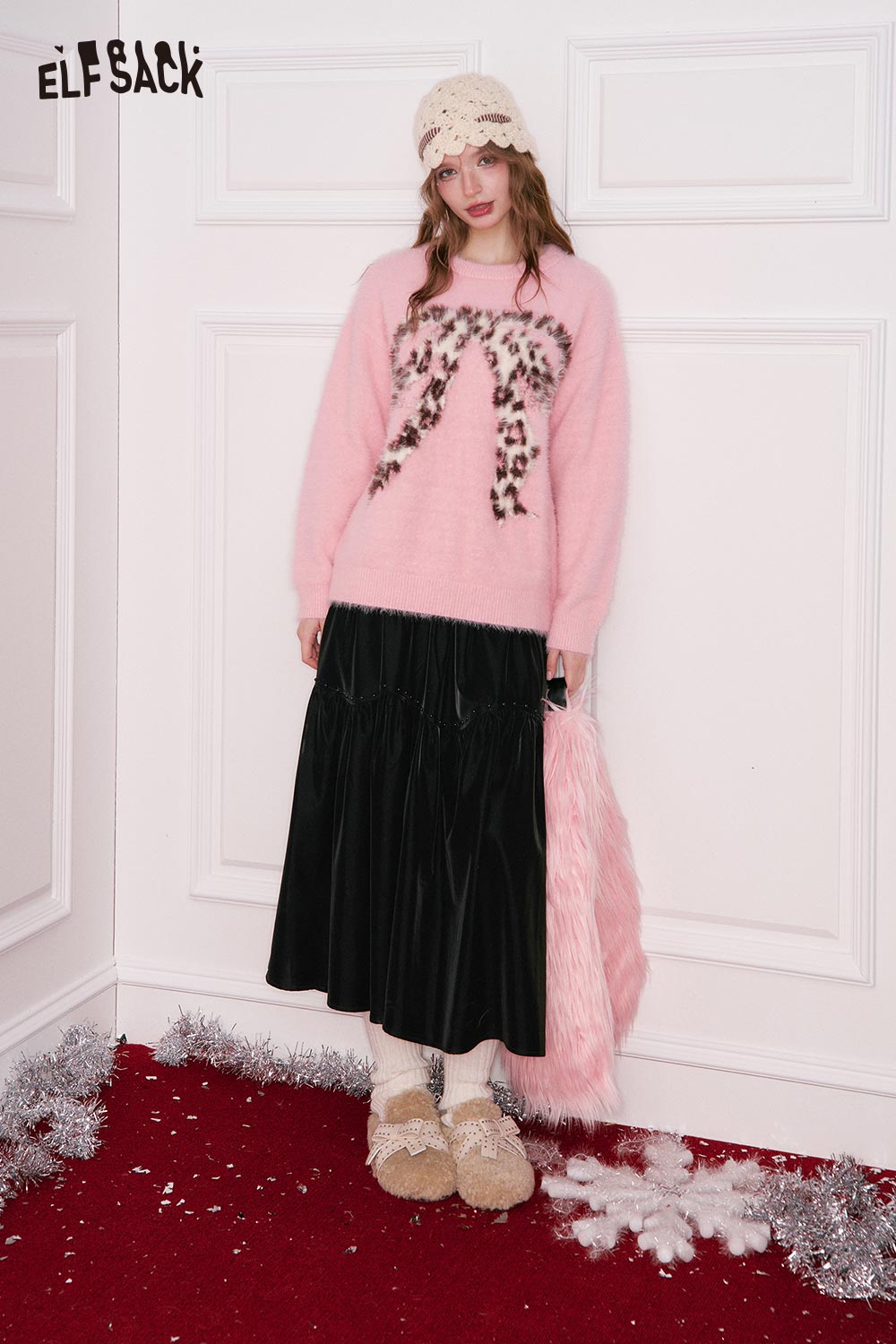 ELFSACK model wearing a pleated PU leather maxi skirt styled with a pink sweater and accessories