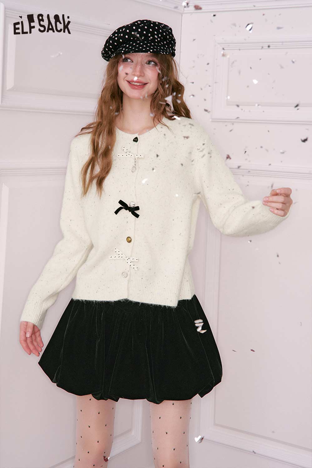 ELFSACK preppy 3D bow cardigan in cream color paired with a black skirt for a stylish look