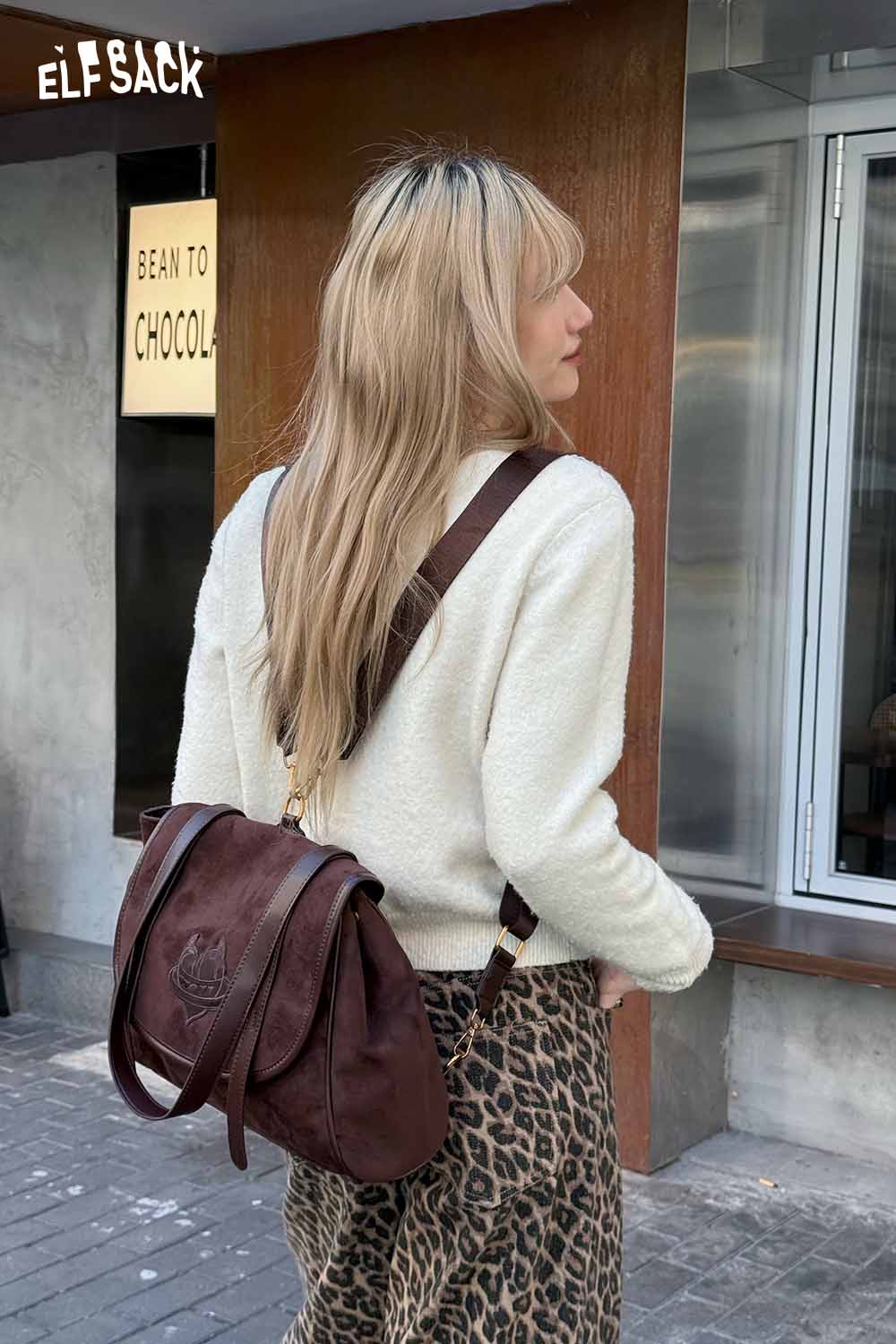 Brown preppy suede backpack for women stylishly worn with a sweater and leopard print skirt