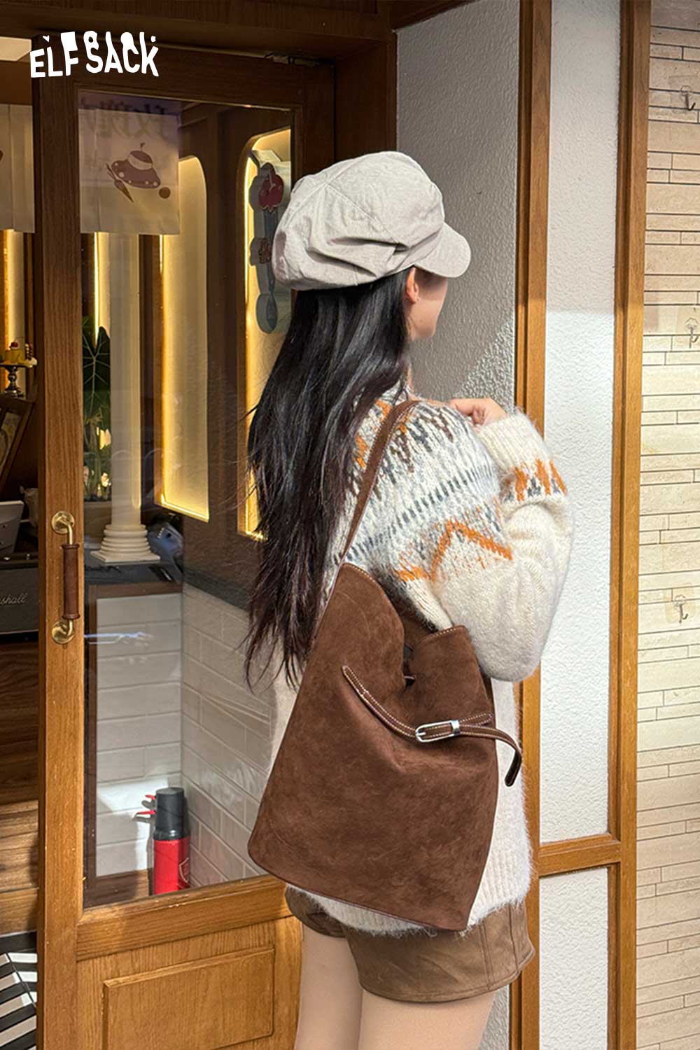 Woman wearing a cozy sweater and cap, carrying a PU leather bucket bag for women in brown