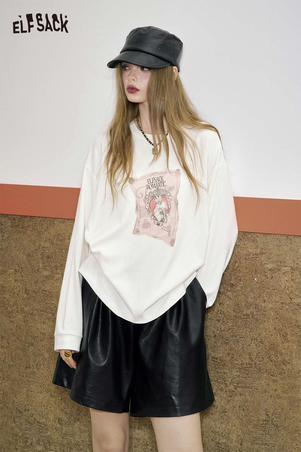 ELFSACK PU leather pleated shorts paired with a graphic sweatshirt and stylish cap for a trendy look