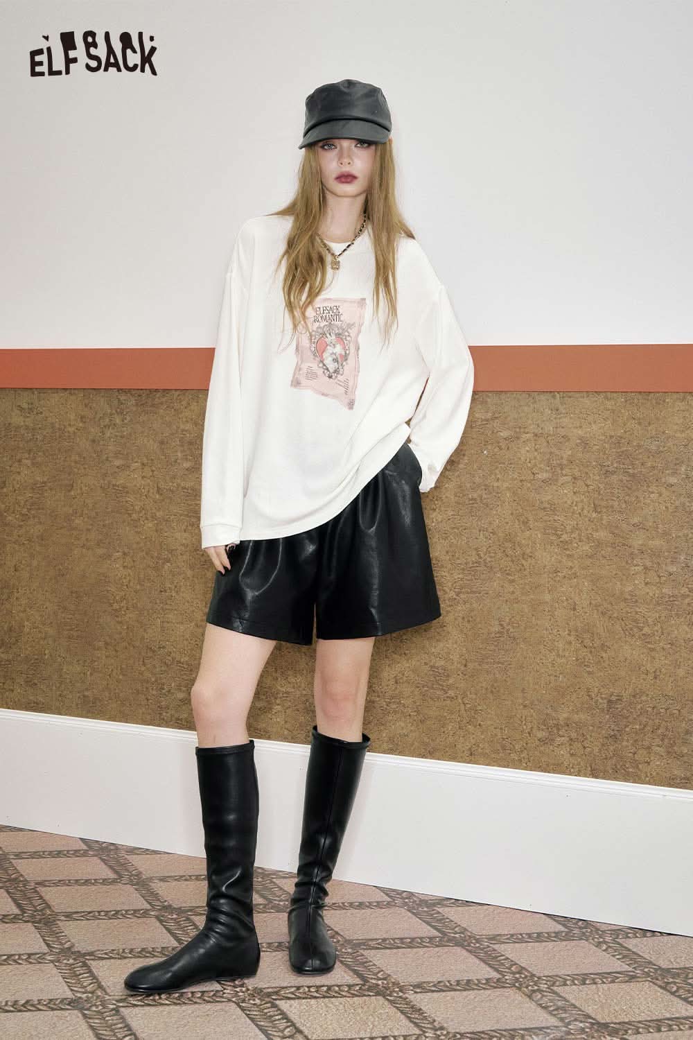 Model wearing ELFSACK PU leather pleated shorts styled with a graphic tee and knee-high boots