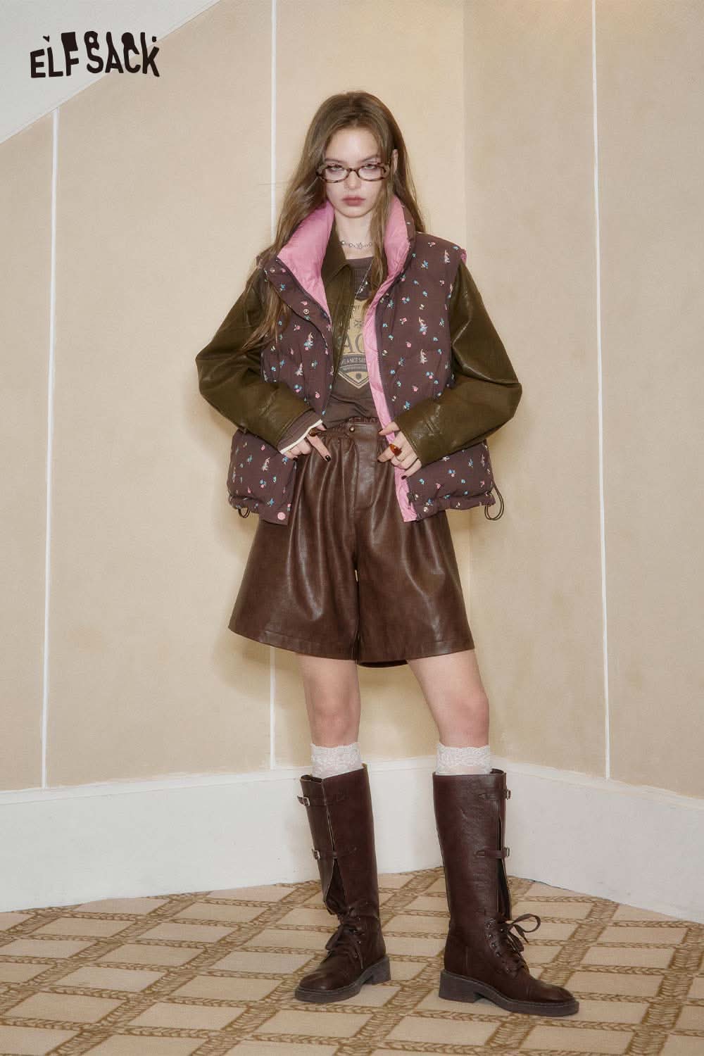 Model wearing ELFSACK PU leather pleated shorts paired with a stylish vest and knee-high boots