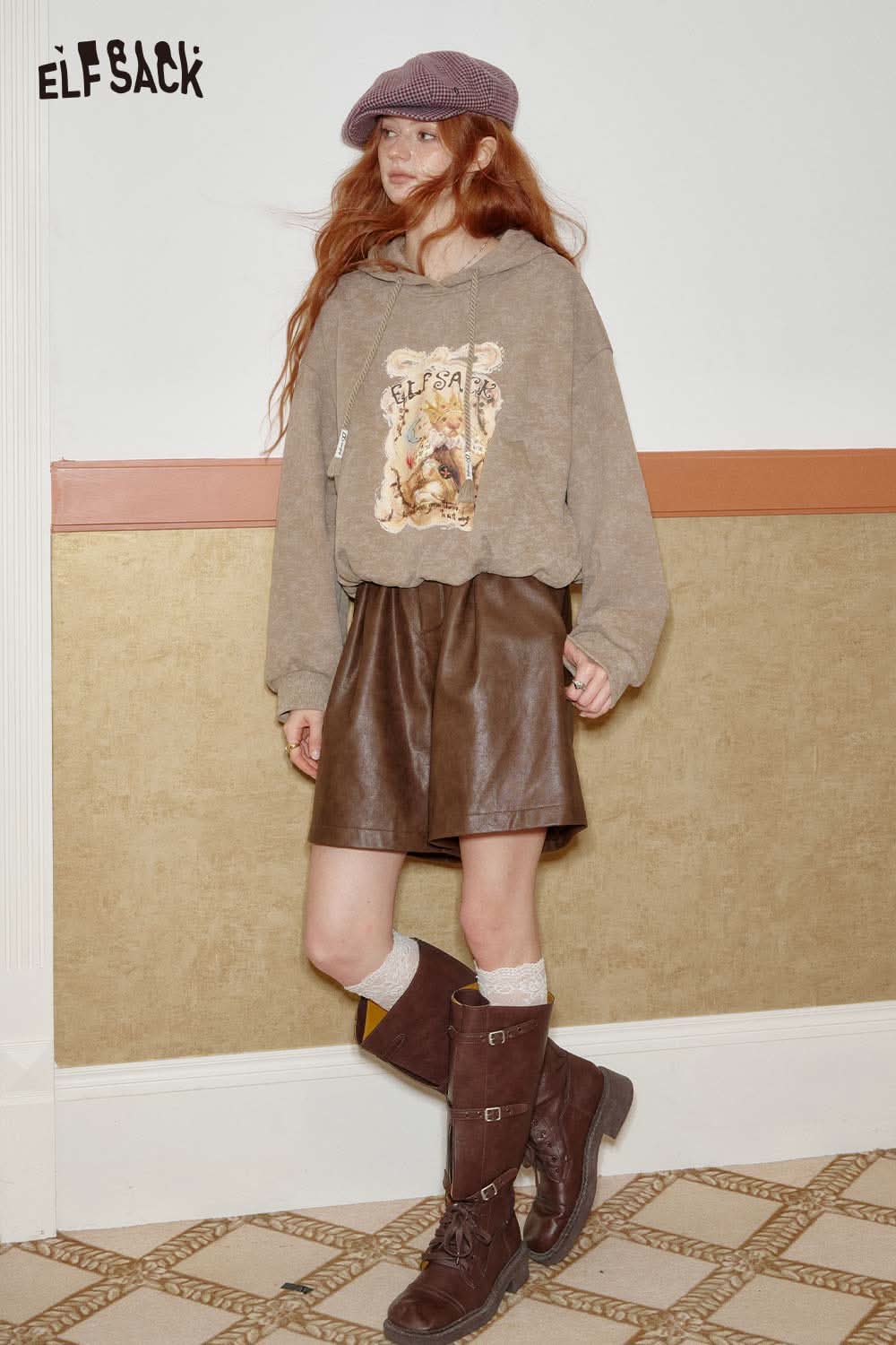 Stylish model wearing ELFSACK PU leather pleated shorts with a cozy hoodie and trendy boots