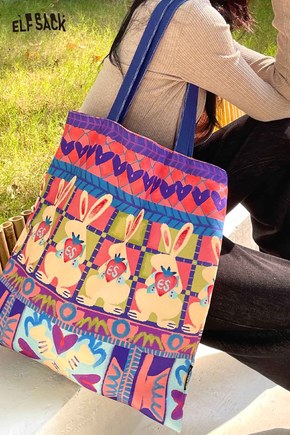 Colorful ELFSACK rabbit graphic tote bag with vibrant bunny designs and sturdy blue straps