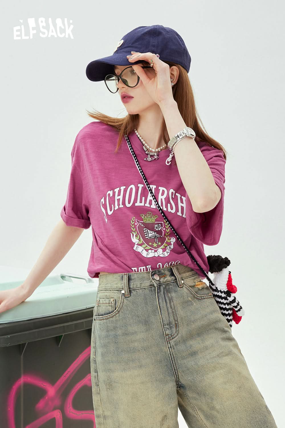 ELFSACK pink Graphic Print T-shirt with rolled sleeves worn with casual jeans and a navy cap