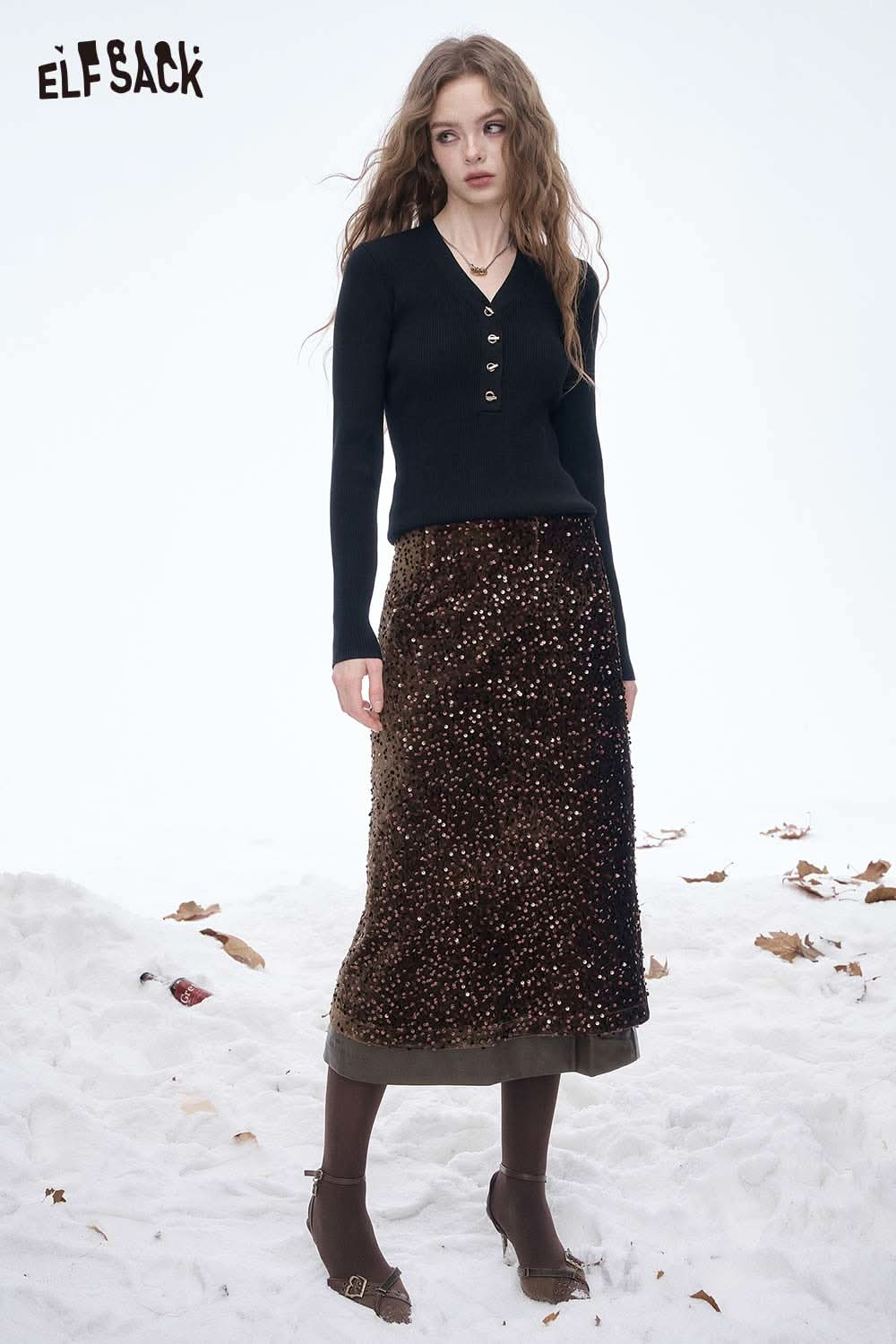 ELFSACK sequin faux leather long skirt paired with a black button-up sweater on a snowy background