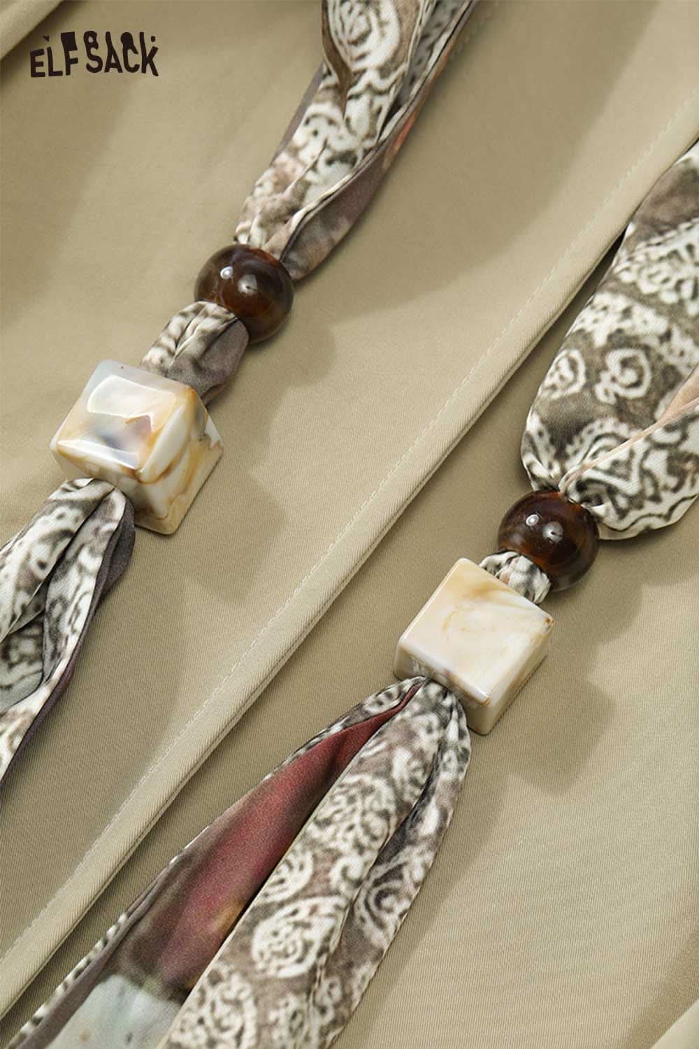 Close-up of an ELFSACK minimalist short jacket for women featuring stylish tie details and unique embellishments