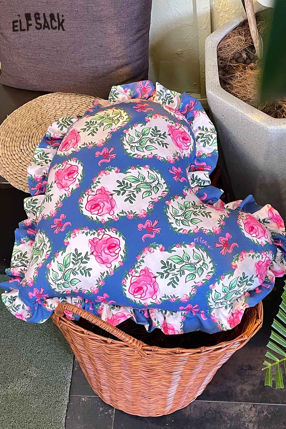 ELFSACK heart shaped rose pillow with blue ruffled edge and pink rose print in wicker basket