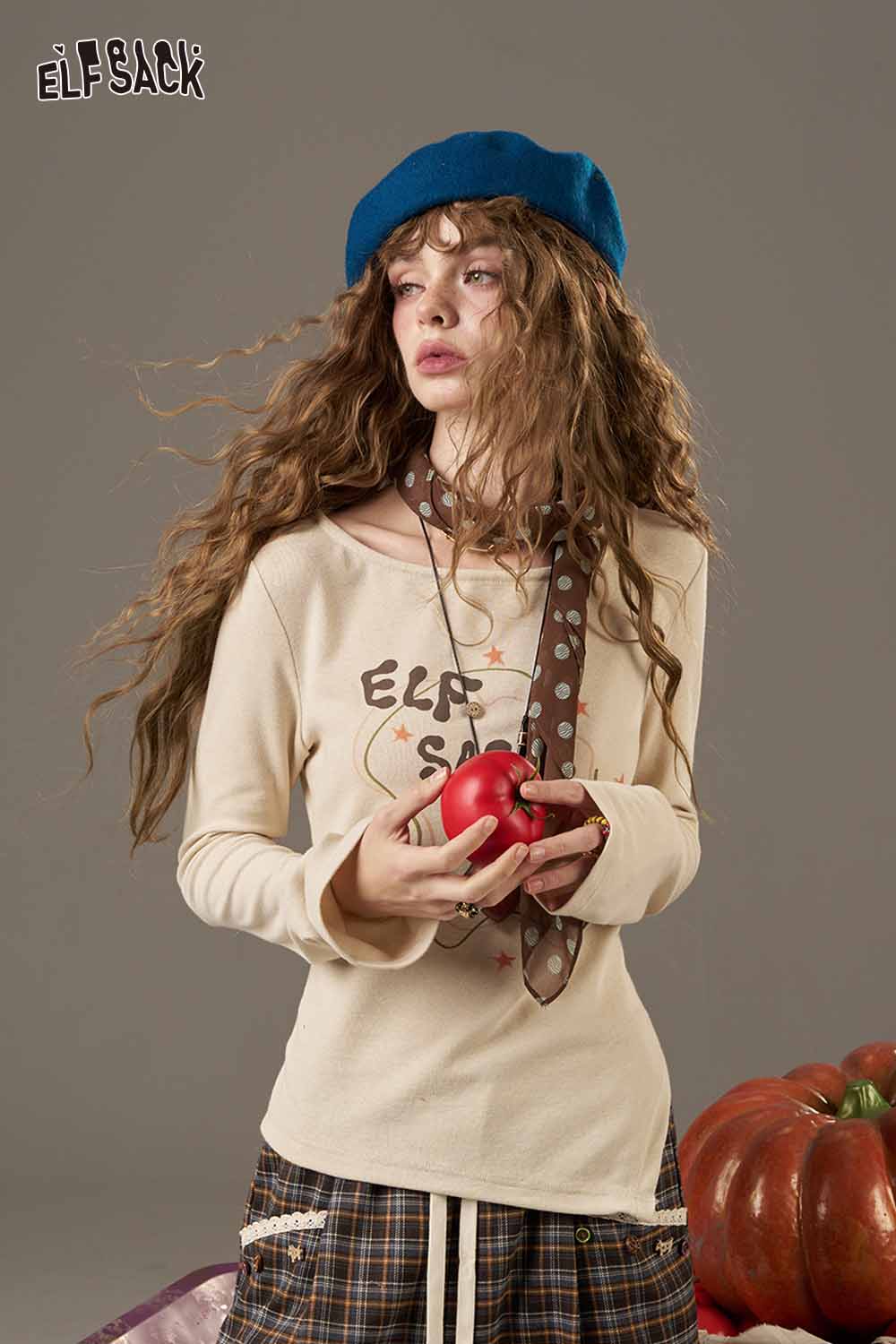 Woman wearing a soft pumpkin beanie for women, styled with a beige top and holding an apple