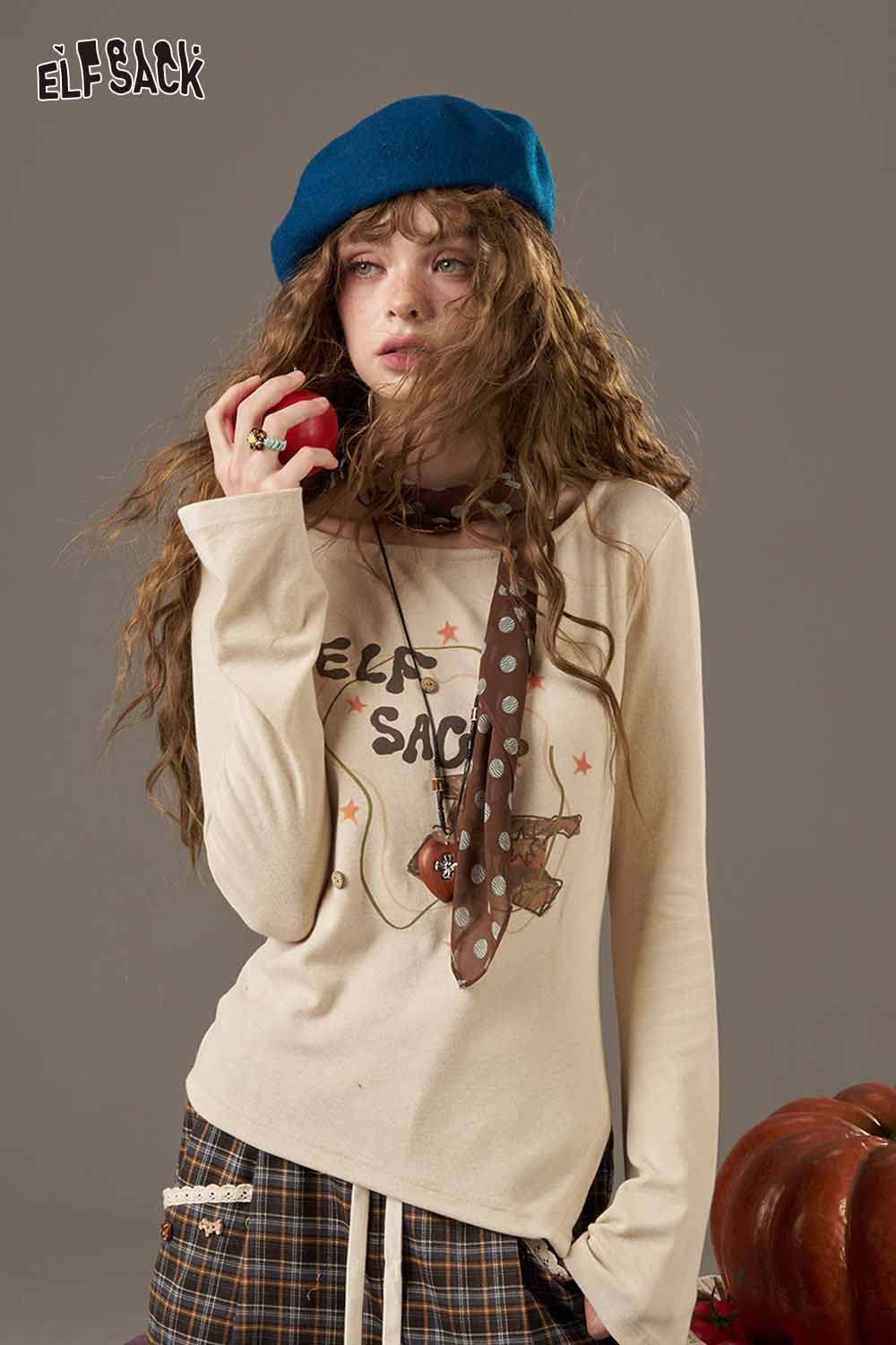 Model wearing a soft pumpkin beanie for women with a playful graphic tee and casual plaid pants