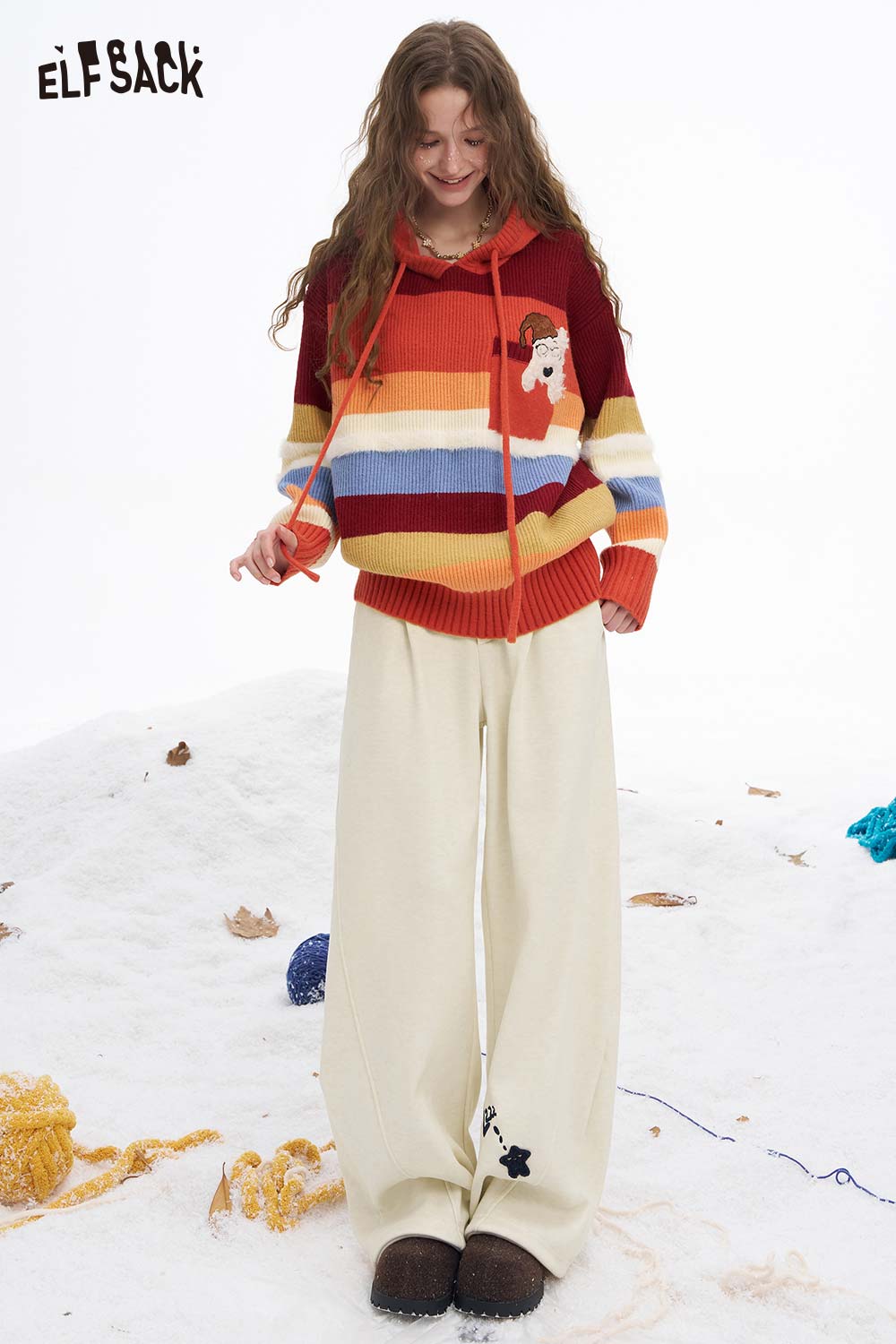 ELFSACK star graphic floor length pants in cream color paired with a colorful striped sweater