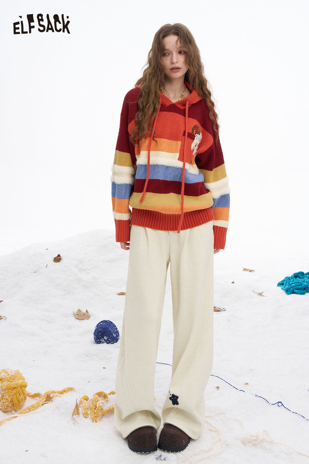 ELFSACK star graphic floor length pants in cream, paired with a colorful striped sweater