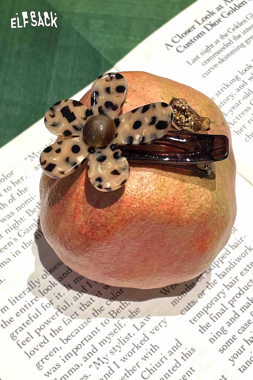 ELFSACK tortoise shell floral hairpin showcasing a flower design on a clip positioned on an apple