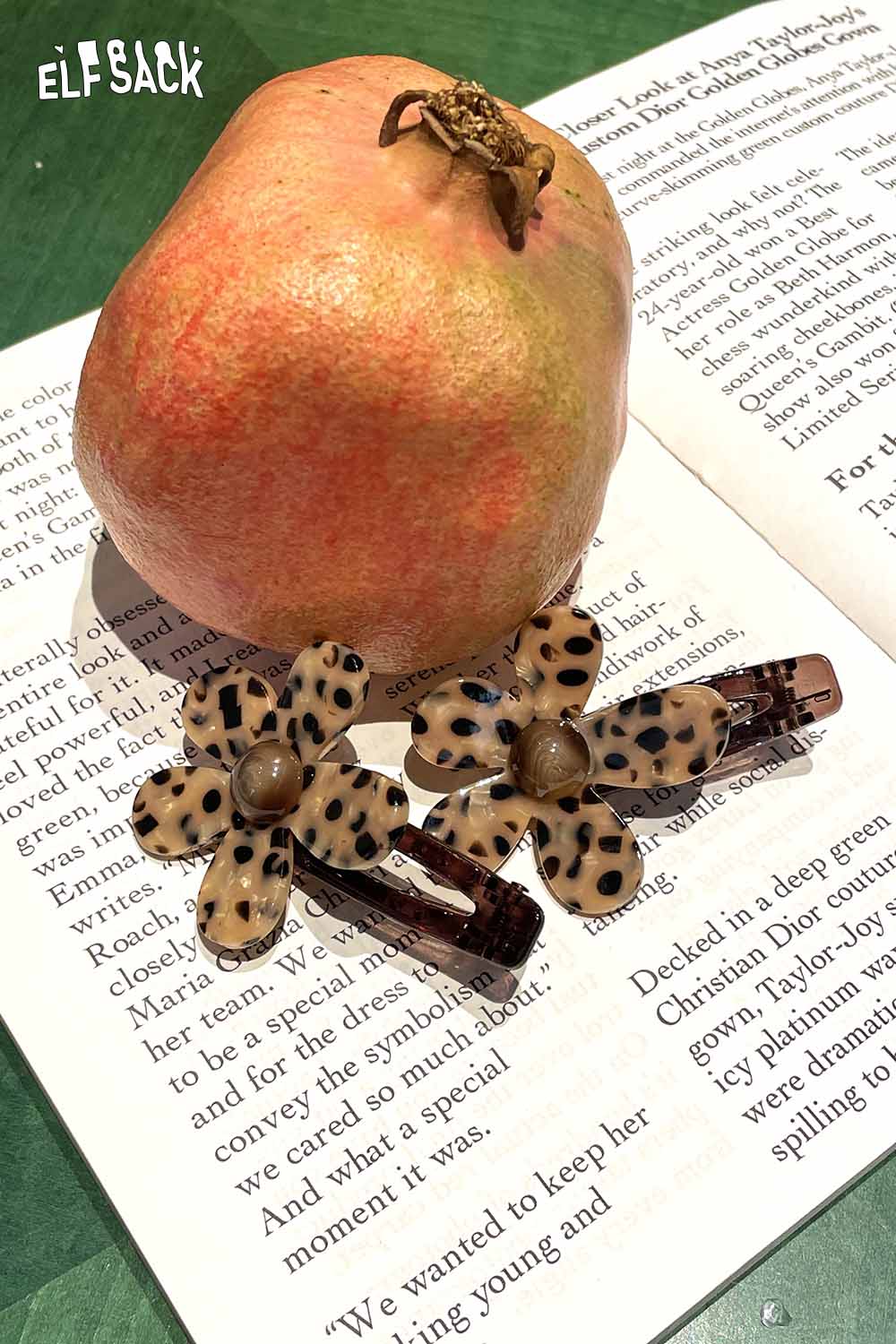 ELFSACK tortoise shell floral hairpin set on an open book with a fresh apple for contrast