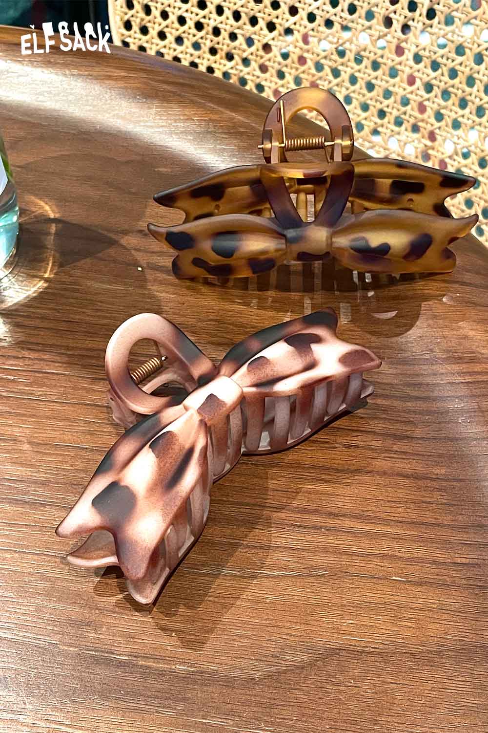 ELFSACK tortoiseshell bow hair claw in two styles on a wooden table, perfect for stylish hairdos.