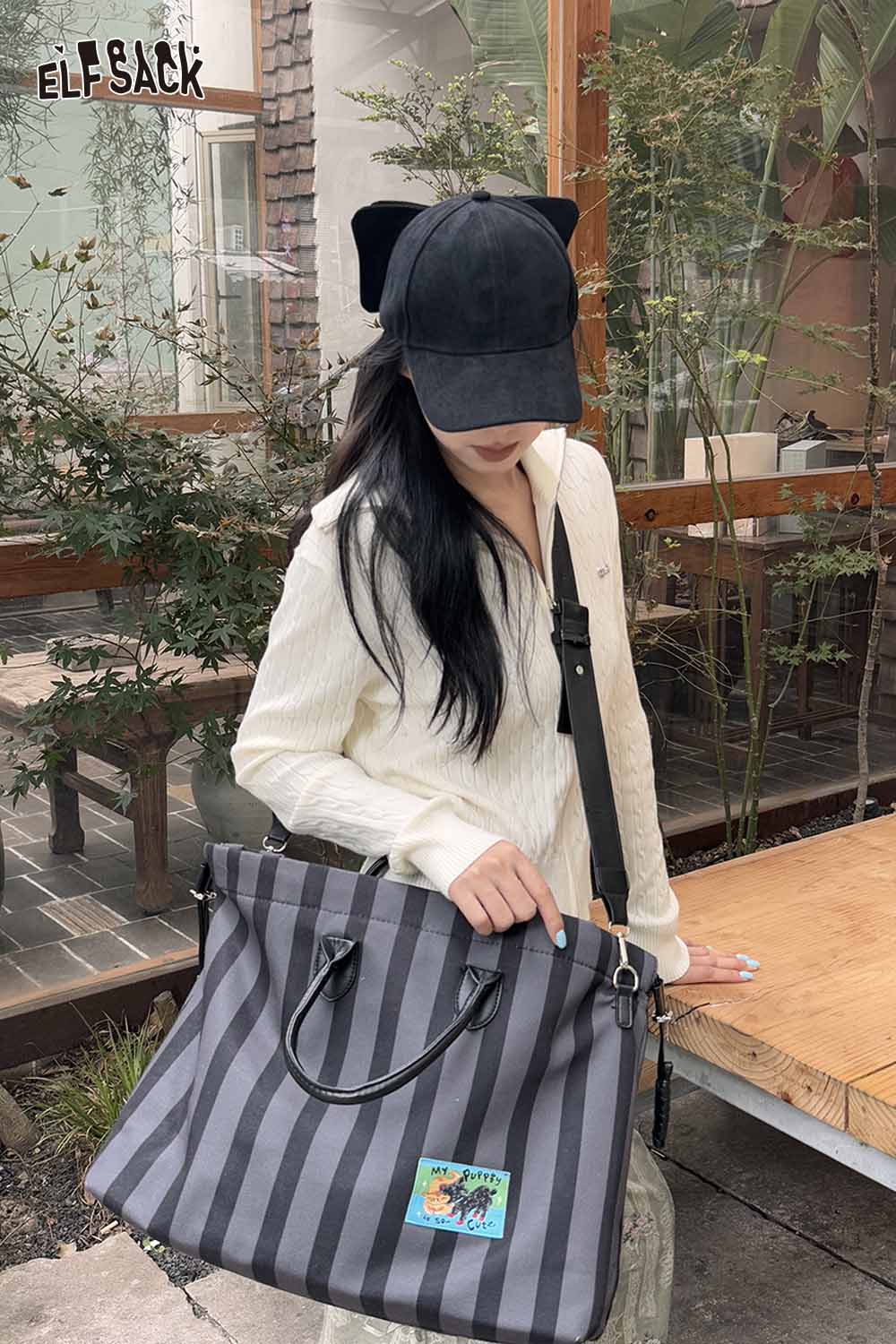 ELFSACK velour bow baseball cap in black worn with a stylish outfit and striped tote bag