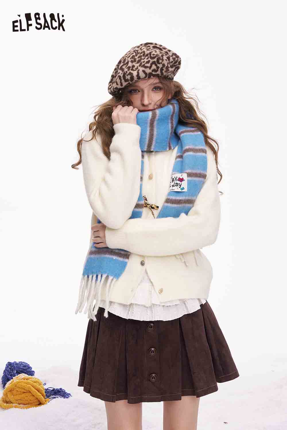 ELFSACK preppy striped fringe scarf in blue and brown paired with a cozy cream cardigan
